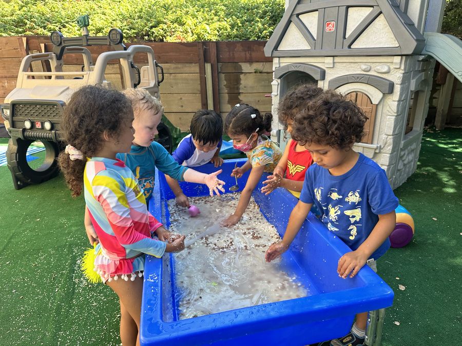 Children playing at a water sensory table at Butterflies Academy summer camp
