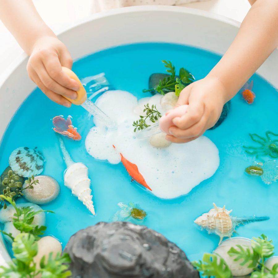 Child exploring a sensory water play bin at Butterflies Academy